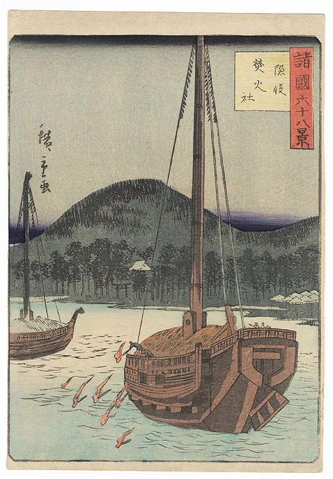 Wooden sailing boats moored below a wooded hillside.